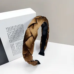 Détail d'un serre-tête tressé en soie marron avec strass dorés et doublure antidérapante