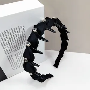 Detail of black twisted headband with large crystals and inner comb teeth for hair styling