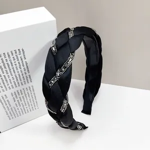Detalle de una diadema trenzada negra con adornos de cristal y textura de seda suave