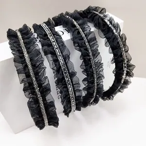 Gros plan de serre-têtes en maille plissée noire avec strass brillants sur boîte blanche