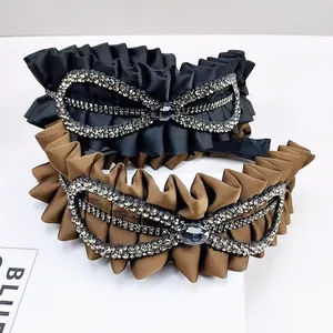 Detailed shot of pleated fabric headband with multi-row rhinestones and oval gemstone