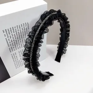 Détail d'un serre-tête en tulle plissé noir avec strass brillants et picots antidérapants
