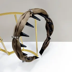 Détail d'un serre-tête en tissu marron orné de pointes noires et de perles de cristal