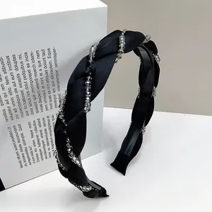Dettaglio del cerchietto in tessuto nero intrecciato con eleganti perline di cristallo
