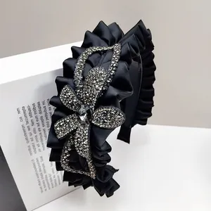 Detail of wide black pleated headband featuring a large sparkling rhinestone butterfly bow