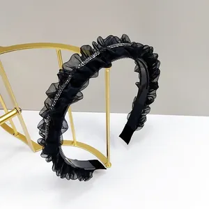 Détail d'un serre-tête en tulle plissé noir orné de strass et muni de dents antidérapantes