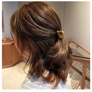 Close-up of a small leopard print hair claw clip on brunette wavy hair in soft light