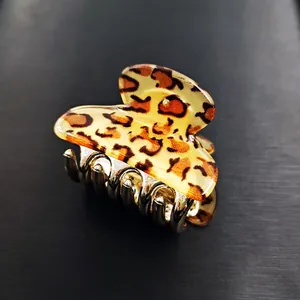 Detail of small leopard print hair claw clip with golden teeth on black background