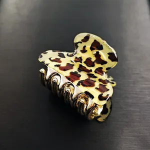 Detail of small gold hair claw clip featuring leopard print pattern and metal teeth
