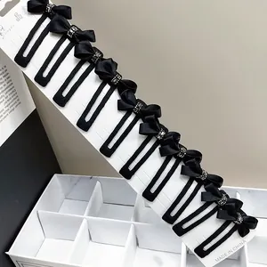 Set mit zehn schwarzen Schleifen-Haarspangen mit Kristallmitte auf weißer Karte
