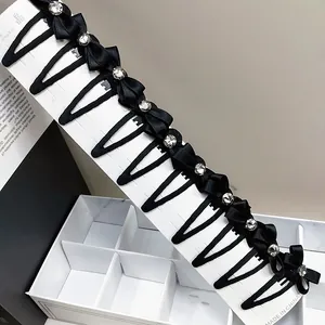 Set mit zwölf schwarzen Satin-Haarschleifen mit glänzenden Strasssteinen auf Karte