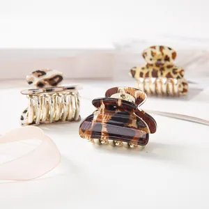 Detailed view of three leopard print resin hair claws with golden metal teeth