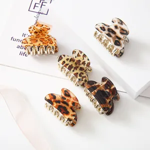 Set of 5 leopard print hair claws with gold metal teeth on white geometric blocks