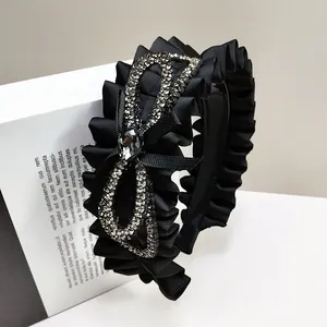 Elegant black satin pleated headband with a large sparkling rhinestone bow and crystal