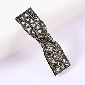 Détail d'une barrette en forme de nœud avec strass triangulaires étincelants sur base noire