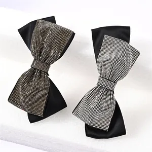 Close-up of elegant black satin bow hair clips with shimmering gold and silver rhinestones