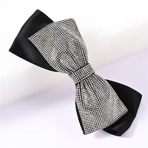 Macro shot of shimmering rhinestones on black satin bow hair clip with luxury texture