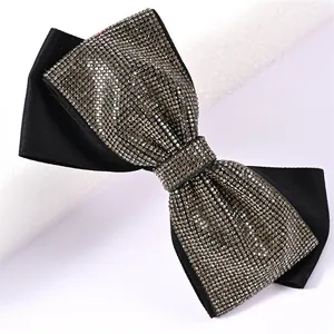 Close-up of black fabric bow hair clip featuring shimmering rhinestones and a spring clip