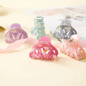 Detailed view of colorful daisy print hair claws in pink, purple, and mint green