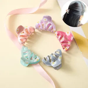 Detailed view of five small candy-colored daisy hair claws in pink, purple, and mint green