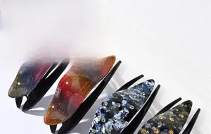 Detail view of colorful swallowtail hair claws with marble textures and rhinestones