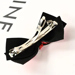 Macro detail of red rhinestone bow hair clip showing secure silver metal spring clip back