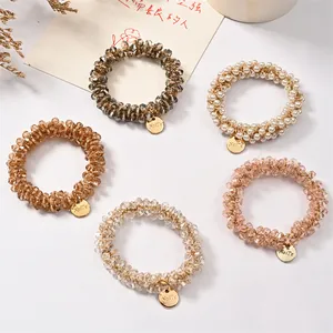 Five elegant elastic hair ties with pearls and crystal beads on a clean white background