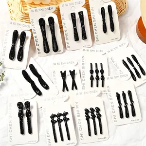 Detalle de varias pinzas para el cabello con diamantes negros en cartón con diseños