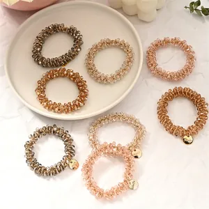 Macro shot of 7 beaded hair ties in Morandi colors with crystals on a ceramic tray
