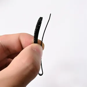Detalle de pinza de pelo negra grande con pedrería brillante que muestra el grosor lateral