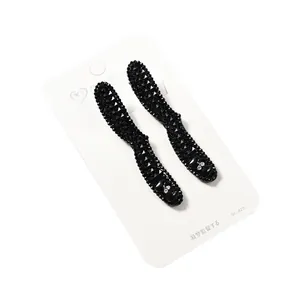 Elegantes pinzas para el cabello con cuentas negras y lazo de strass en tarjeta blanca