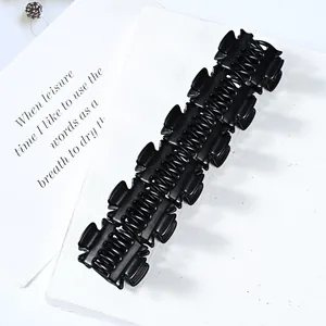 Glossy black banana hair clip with sturdy double teeth on a minimalist display