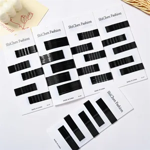 Détail de barrettes noires en métal aux textures lisses et ondulées sur cartes blanches