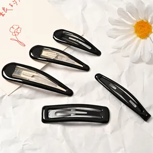 Detalle de cuatro pinzas para el cabello negras brillantes sobre fondo floral minimalista