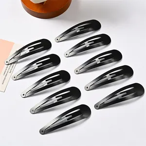 Set de 10 pinzas para el cabello gota negro mate dispuestas sobre superficie decorativa