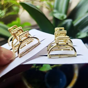 Minimalistische gouden metalen mini haarklemmetjes op displaykaart met natuurlijke achtergrond