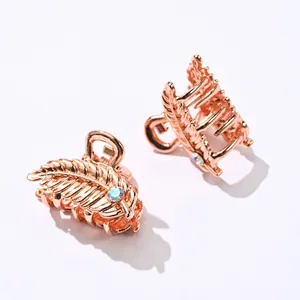 Detailed macro view of leaf-shaped rose gold metal hair claws with crystal inlay