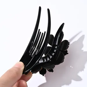Primer plano de una pinza para el pelo con flor negra, toques dorados y dientes de agarre