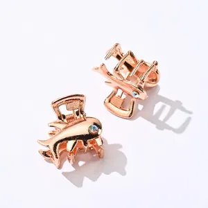 Macro view of rose gold fish-shaped metal hair clips with sparkling rhinestone eyes