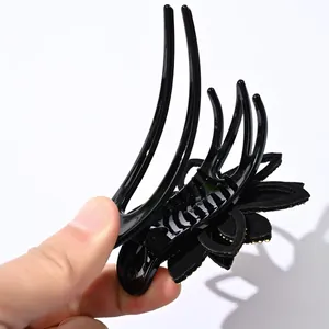 Detalle de pinza para el pelo con flores, pétalos negros mates y brillantes strass dorados