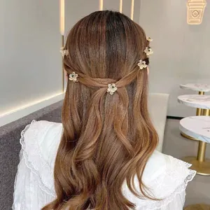Detalle de pinzas para el pelo de flores crema con gemas verdes en peinado elegante