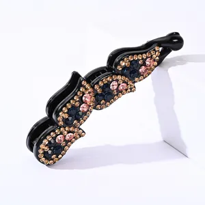 Pince banane scintillante en strass avec cristaux colorés sur support géométrique blanc