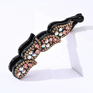 Barrette banane noire ornée de strass champagne et roses sur un support blanc élégant