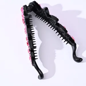 Close-up of black banana hair clip with pink rhinestones and internal grip teeth