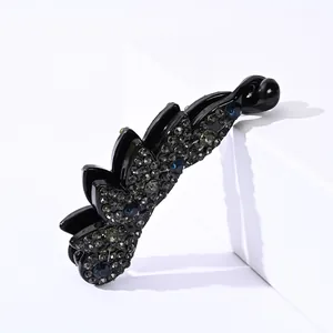 Close-up of black banana clip featuring pavé-set grey rhinestones and blue crystals