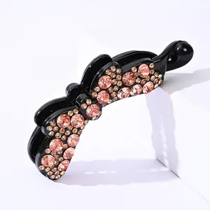 Dettaglio di strass champagne e rosa scintillanti su una clip per capelli a fiocco