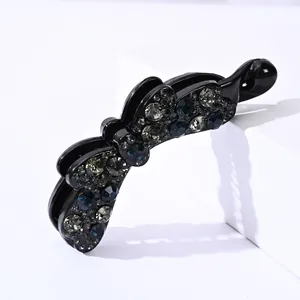 Dettaglio del fermaglio a banana con strass blu e grigi scintillanti su resina nera