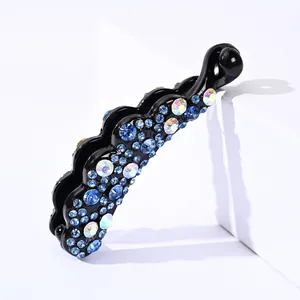 Détail de pince à cheveux banane avec strass bleus et arc-en-ciel sur résine noire ondulée