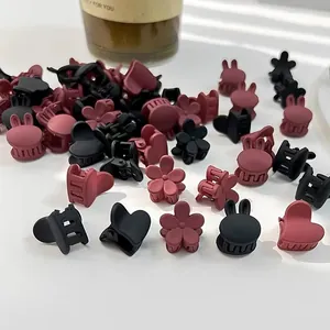 Detalle de mini pinzas para el cabello en forma de corazón y conejo en negro y rojo mate