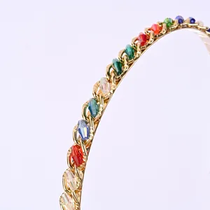 Détail d'un serre-tête doré orné de cristaux facettés colorés au fini métallique